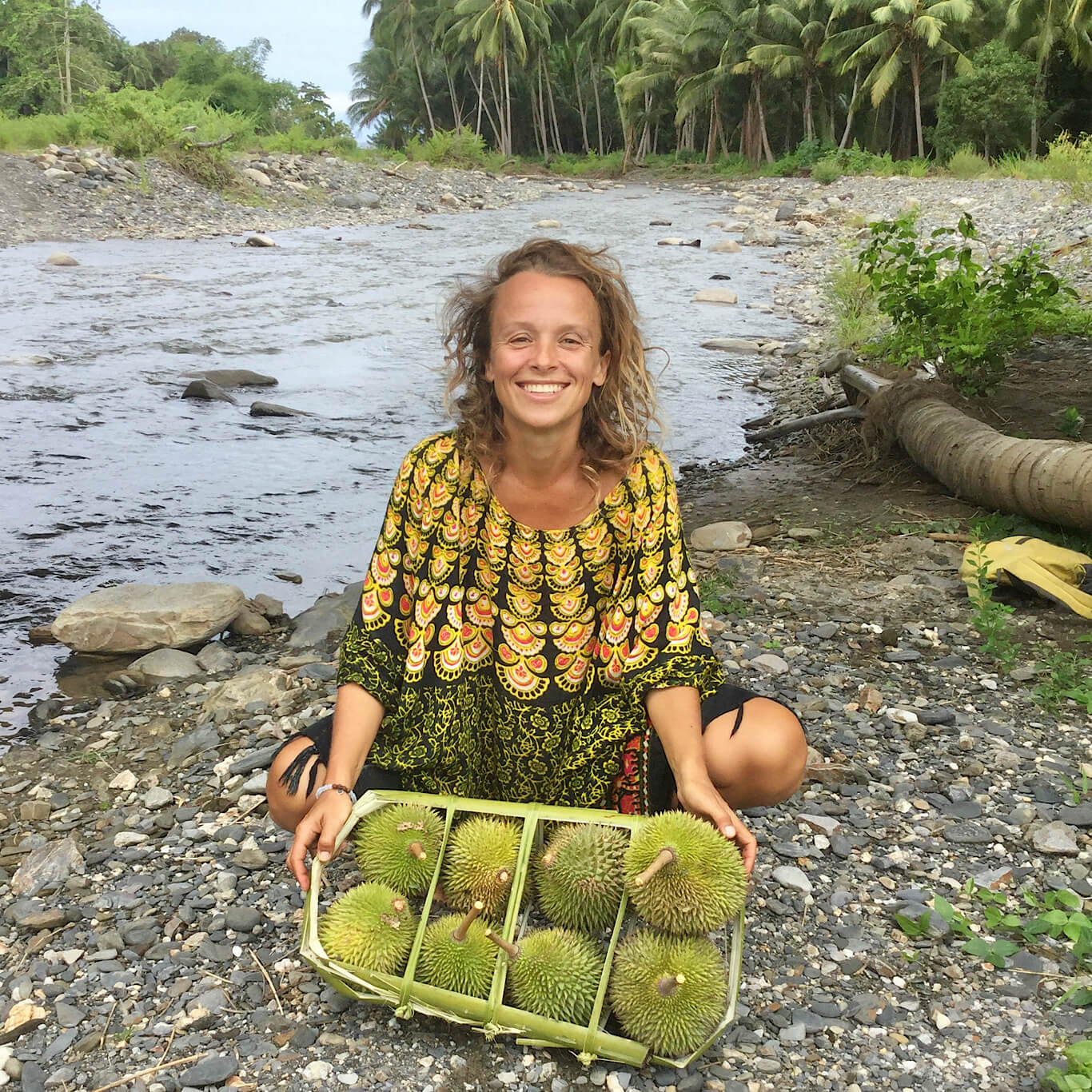 Tina from Fit Shortie posing for a picture with durian at a jungle river in Seram Island